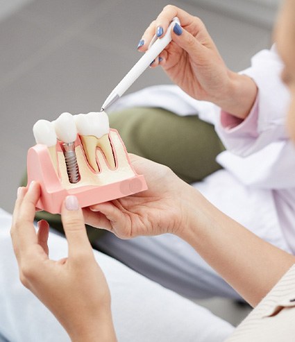 a patient holding a dental implant model