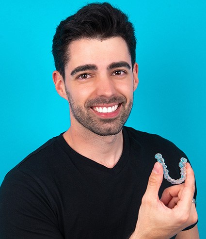 Man in black shirt holding an Invisalign aligner