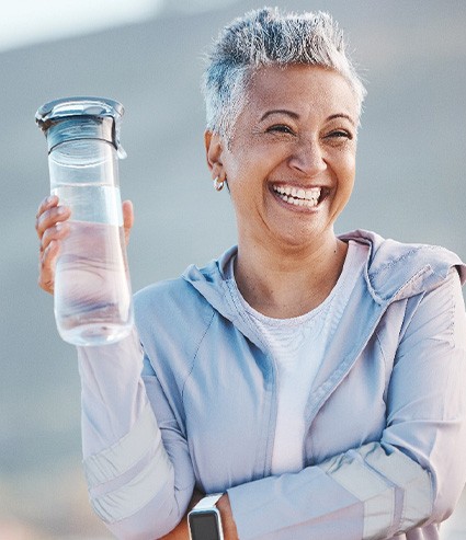 Woman smiling with water bottle on hike outside