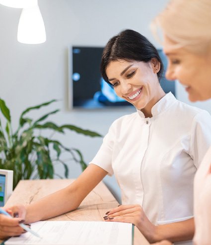 Smiling dental assistant showing patient forms