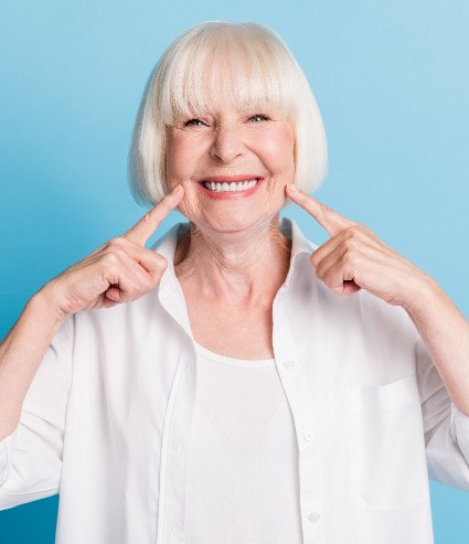 Woman smiling and pointing to her dentures