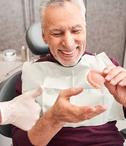 A dentist showing a full denture to a senior patient