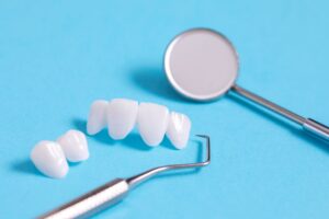 Veneers next to dental instruments on a light blue background