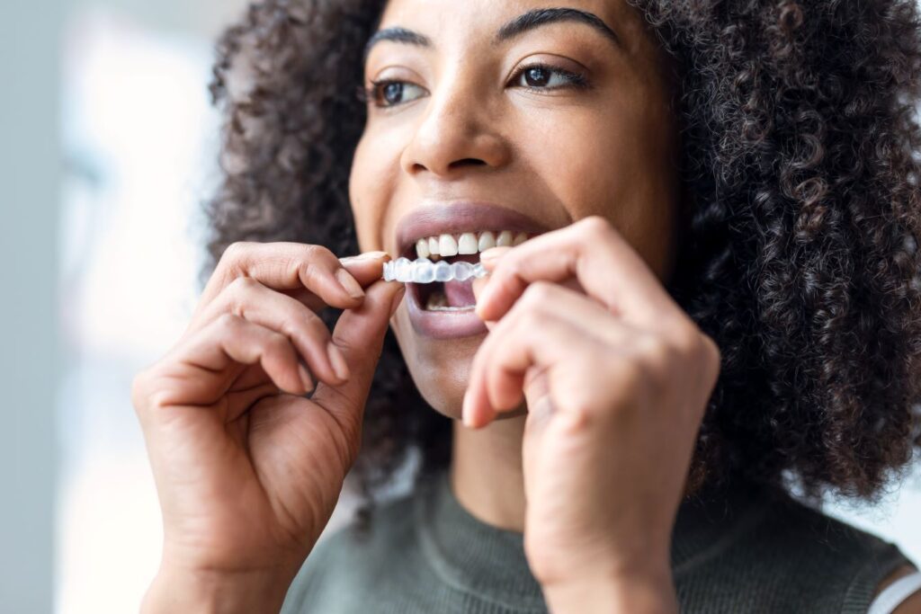 A woman putting on an Invisalign aligner.