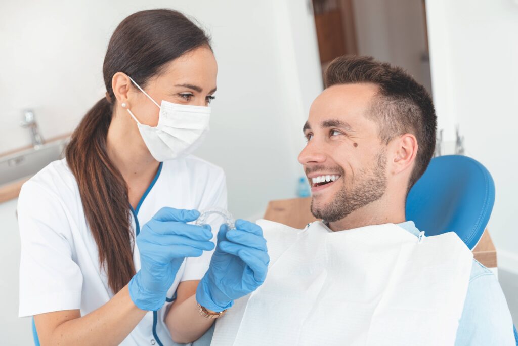 Dentist holding Invisalign aligner while smiling at patient